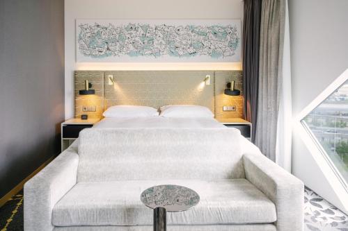 a bedroom with a bed and a couch and a window at Hilton Amsterdam Airport Schiphol in Schiphol