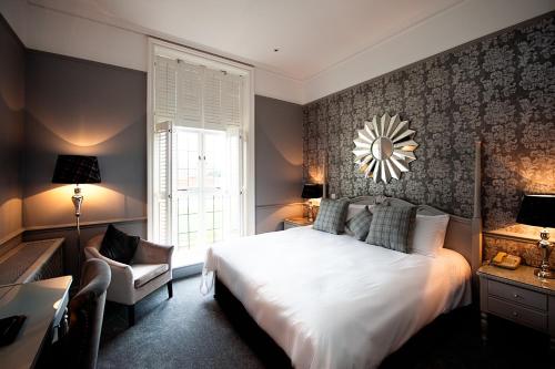 a bedroom with a large white bed and a chair at Greenwoods Hotel & Spa in Stock
