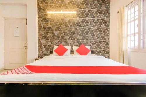 a bedroom with a large bed with red pillows at Super Hotel O Kamini in Patna