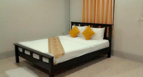 a bedroom with a bed with yellow and white pillows at Lanta MSD House 1 in Ko Por