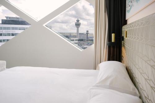 a bedroom with a white bed and a window at Hilton Amsterdam Airport Schiphol in Schiphol