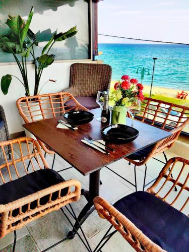 a wooden table with chairs and a table with flowers at Lux Suite Sea Front Avra in Pefkohori