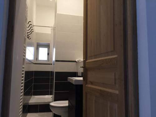 a bathroom with a toilet and a wooden door at Gite de charme à Frémainville dans le vexin in Frémainville