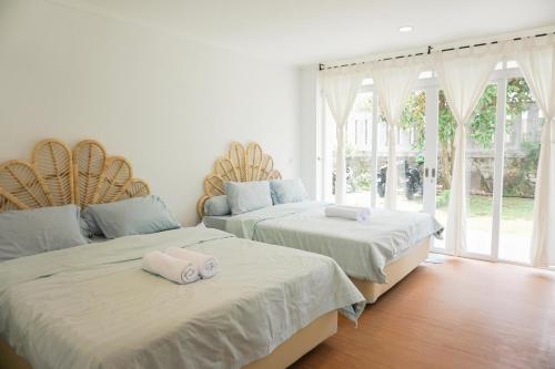 two beds sitting in a room with windows at Over Easy Apartment in Bandung