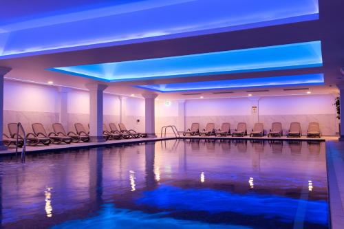 uma piscina com cadeiras num quarto com luzes azuis em Greenwoods Hotel & Spa em Stock