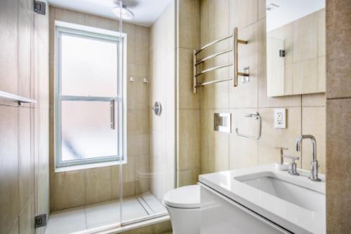uma casa de banho com um WC, um lavatório e uma janela em Relaxing 3BR Apartment em Nova Iorque