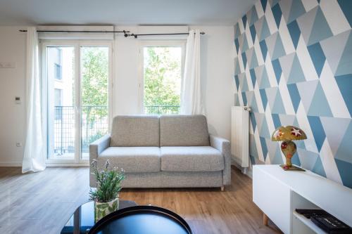 un salon avec un canapé et une table dans l'établissement Blue Pearl By Plaza, à Montévrain