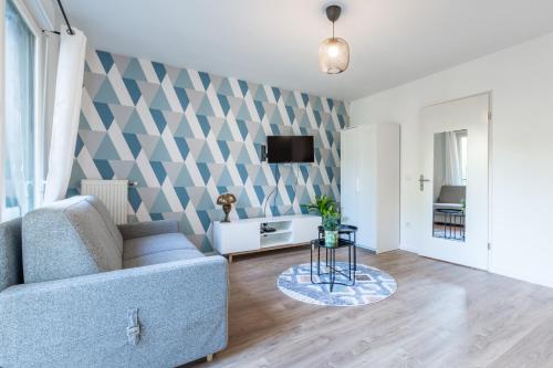 un salon avec un canapé et une télévision sur un mur dans l'établissement Blue Pearl By Plaza, à Montévrain