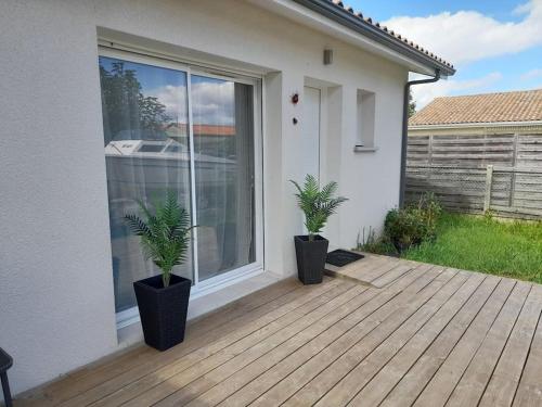 Studio tout confort + terrasse في غوجان-ميستراس: اثنين من النباتات الفخارية تقف على سطح السفينة أمام المنزل