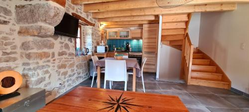 cocina y comedor con mesa y pared de piedra en Gîte la Cardabelle en Ispagnac