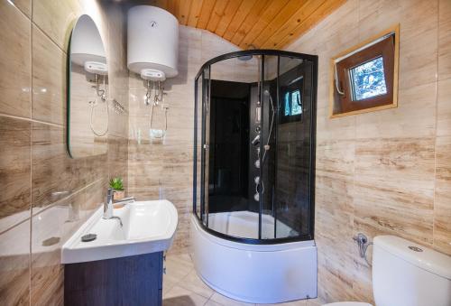 a bathroom with a sink and a shower and a toilet at Domki Letniskowe Forest nad morzem in Darłowo