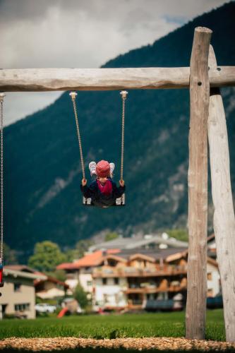 a doll on a swing with a city in the background at Wagner's Aparthotel in Pertisau