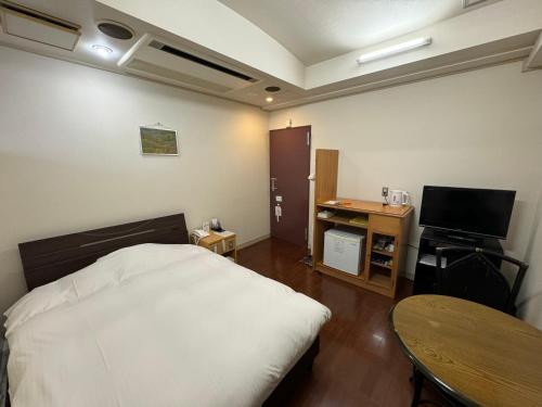 a bedroom with a bed and a table and a television at ホテルカスカベ Hotel Kasukabe in Kasukabe