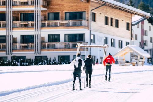 three people are walking in the snow in front of a building at Wagner's Aparthotel in Pertisau
