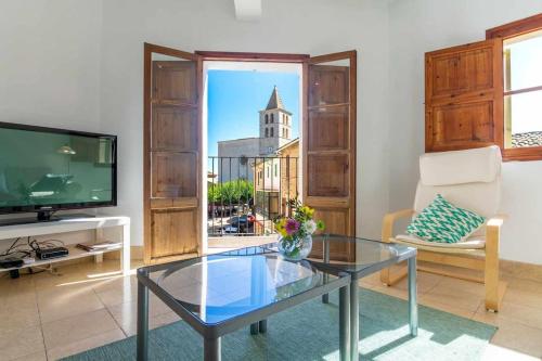a living room with a glass table and a tv at Maca Sol, adosado con vistas a la montaña in Campanet