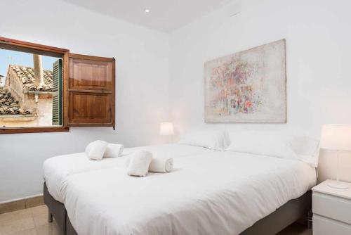 a white bedroom with a large bed and a window at Maca Sol, adosado con vistas a la montaña in Campanet