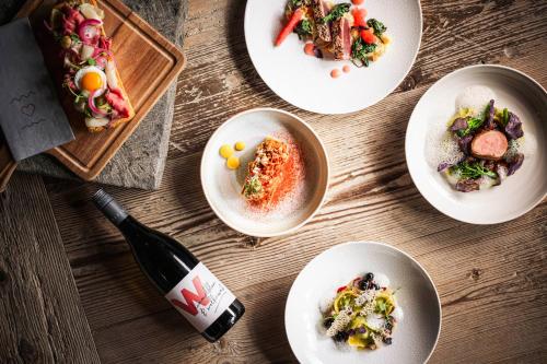 a table with plates of food and a bottle of wine at Wagner's Aparthotel in Pertisau