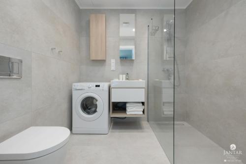 a bathroom with a washing machine and a sink at Shellter Apartments 117 L - by Jantar Apartamenty in Rogowo