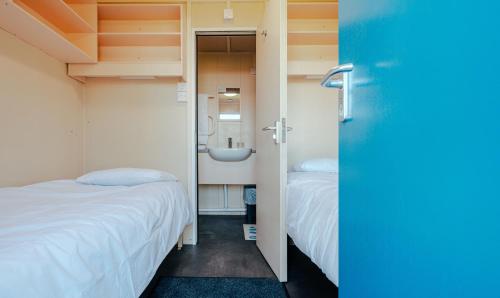 a room with two beds and a bathroom with a sink at IOMTT Village at Isle of Man TT in Douglas