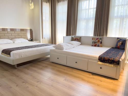 two beds in a bedroom with wooden floors and windows at Puding Hotel in Antalya