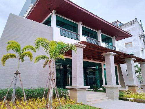 un edificio con balcón y palmeras delante de él en Mayflower Grande Suite Hotel, en Phitsanulok