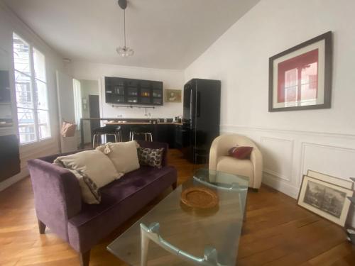 - un salon avec un canapé violet et une table en verre dans l'établissement Aux Terrasses de la Lune, à Paris