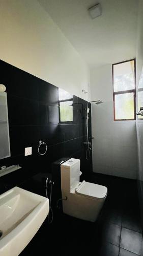 a bathroom with a white toilet and a sink at New Stay Inn in Bentota