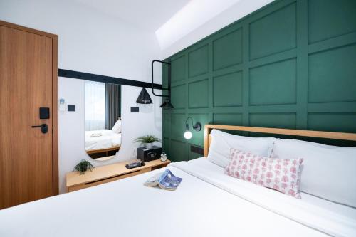a bedroom with a large white bed with a green wall at Habyt Cantonment - formerly Hmlet Cantonment in Singapore