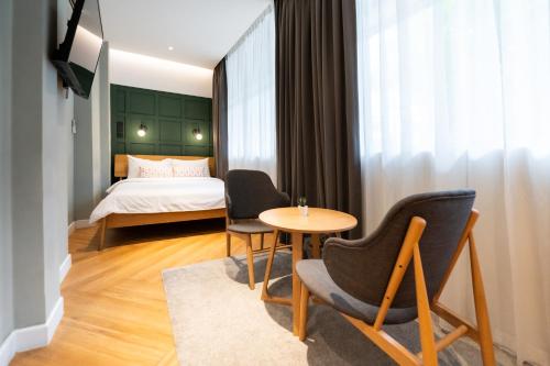 a hotel room with a bed and two chairs and a table at Habyt Cantonment - formerly Hmlet Cantonment in Singapore