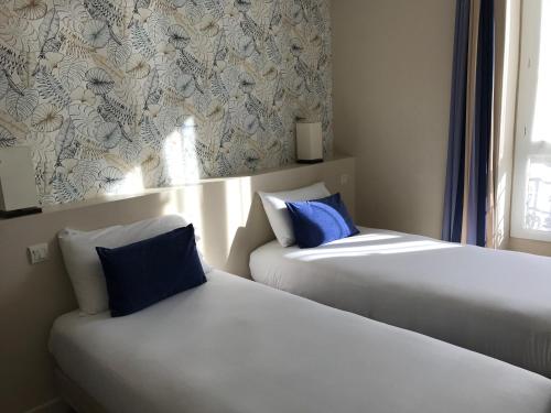 two beds sitting next to each other in a room at Hotel Le Havre Bleu in Beaulieu-sur-Mer