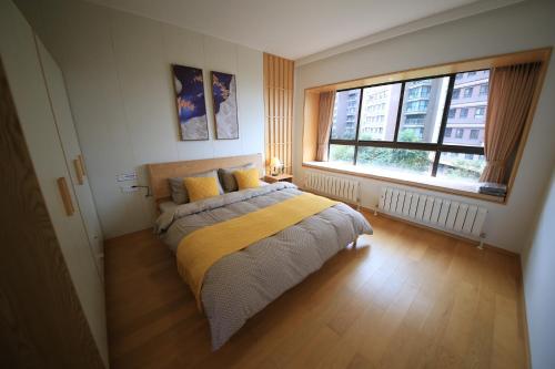 a bedroom with a bed with a yellow blanket and two windows at Colorful Yunnan Absolutely Beautiful Dian B&B in Kunming