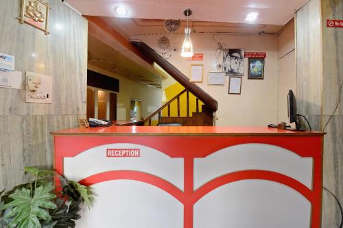 a lobby with a red and white reception counter and a staircase at OYO Hotel Sunbeam in Shamshi