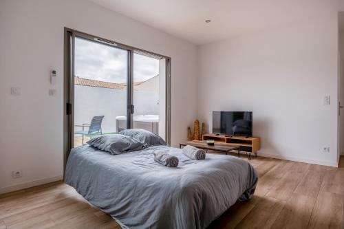 um quarto com uma cama grande e uma janela grande em Un cocon climatisé avec jacuzzi em Marsilly