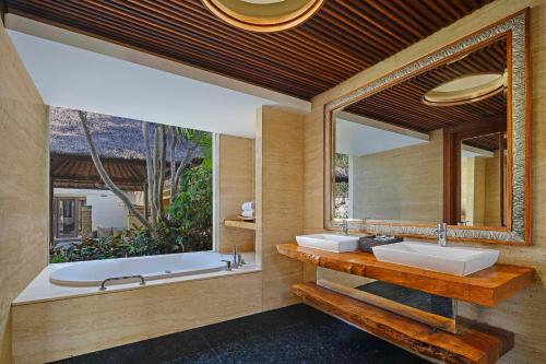 a bathroom with two sinks and a large mirror at Amarterra Villas Resort Bali Nusa Dua, Autograph Collection in Nusa Dua