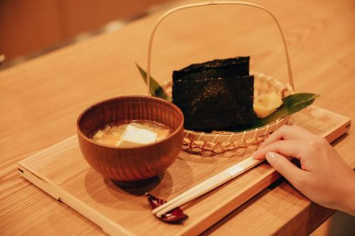 a person holding a chopstick next to a bowl of sushi at KAMAKURA Hotel in Kamakura