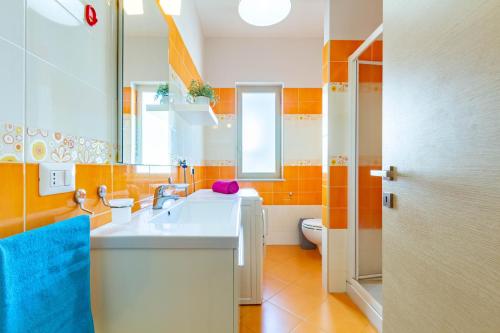 a bathroom with a sink and a mirror and a toilet at Appartamento Minerva int5 - MyHo Casa in Tortoreto Lido
