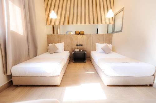 two beds in a hotel room with white sheets at Ennesma Hotel in Casablanca