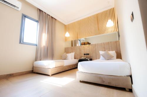 a hotel room with two beds and a window at Ennesma Hotel in Casablanca