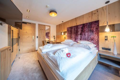 a large white bed in a room with wooden walls at Hotel Wiesental in Obergurgl