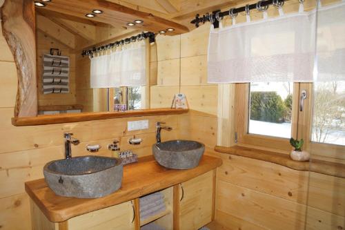 two sinks in a log cabin bathroom with a window at Chalet Bauer in Drachselsried