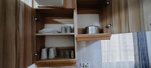a kitchen with wooden cabinets with plates and pans at Premier Stays Ruiru in Ruiru