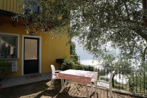 a table and two chairs in front of a house at CASA NAVLA' AppartamentI "Ulivi"- "Fiori" -"Velieri"-"Luna"-"Nido"-"Taverna" in Tignale