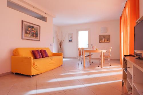 a living room with a yellow couch and a table at CASA NAVLA' AppartamentI "Ulivi"- "Fiori" -"Velieri"-"Luna"-"Nido"-"Taverna" in Tignale