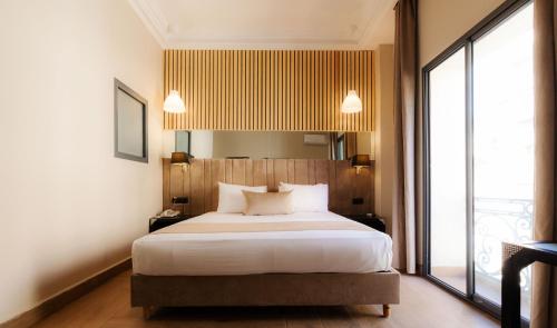 a bedroom with a large bed and a large window at Ennesma Hotel in Casablanca