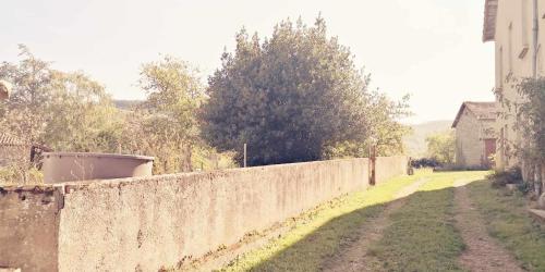 a concrete wall next to a road next to a house at Petit gîte ou chambre d'hôtes 2/4 personnes in Buffières