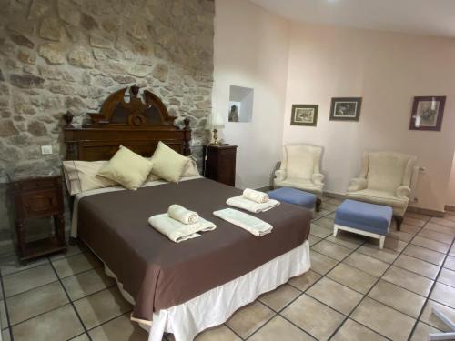 a bedroom with a large bed and two chairs at La del Pozo in Montánchez