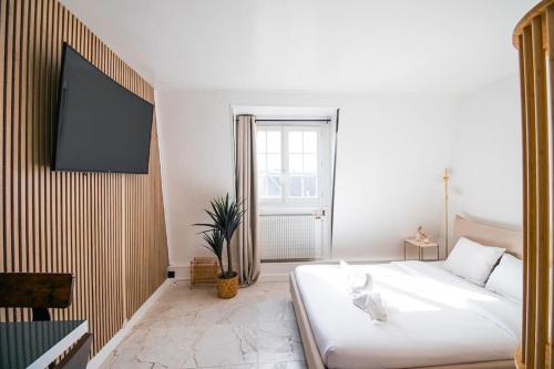 a bedroom with a white bed and a flat screen tv at Typical Parisian Studio in Le Marais in Paris