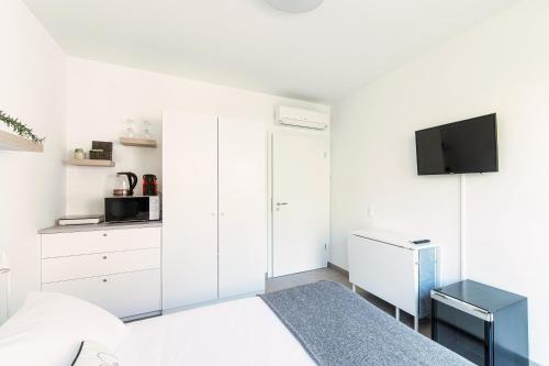 a white bedroom with a bed and a tv at Le Betulle Studios by Quokka 360 - studio apartments by the Origlio lake in Origlio