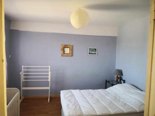 a bedroom with a white bed and a blue wall at Petit gîte ou chambre d'hôtes 2/4 personnes in Buffières