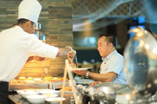 a chef giving a man a plate of food at Ramee Grand Hotel And Spa in Manama